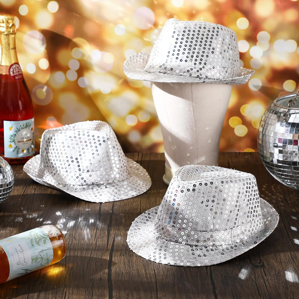 Silver sequin hats on a wooden surface with bottles and disco ball against a blurred bokeh background