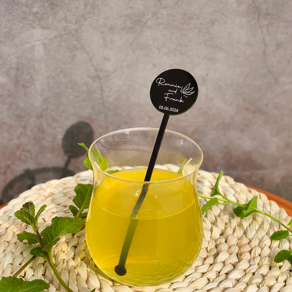 Glass of yellow liquid with a black straw on a woven surface