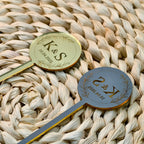 Two gold and silver spoons with engraved initials and dates on a woven surface