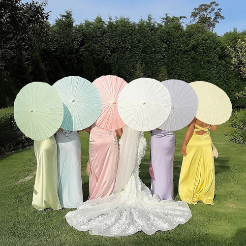 Group of women holding colorful umbrellas with a bride in a white dress.