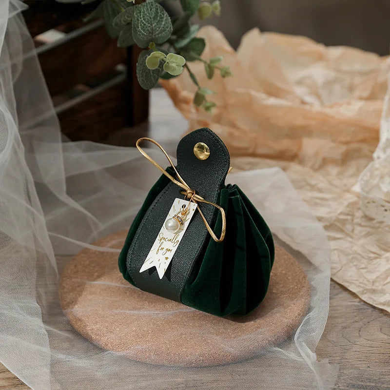 Green velvet pouch with gold ribbon on a wooden surface with a soft, blurred background