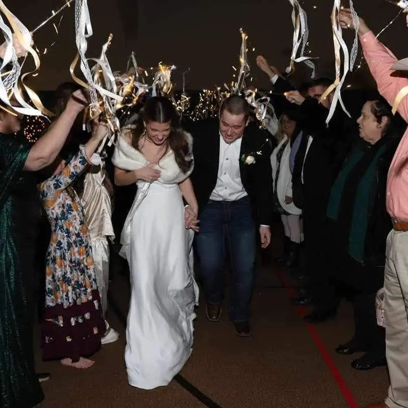 Wedding couple walking through a crowd of people with confetti and streamers.