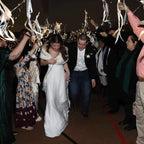 Wedding couple walking through a crowd of people with confetti and streamers.